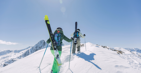 2 skiers walking towards a peak