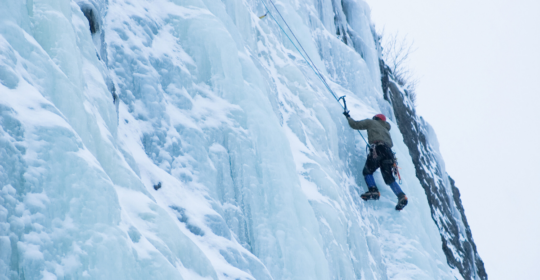 ice climber climbing up a steep ice section