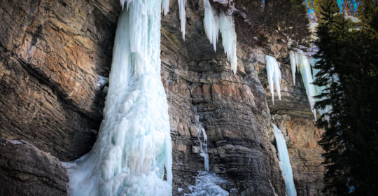 A large frozen waterfall in Vail, Colorado, glistening with layers of ice, a popular winter destination for ice climbers.